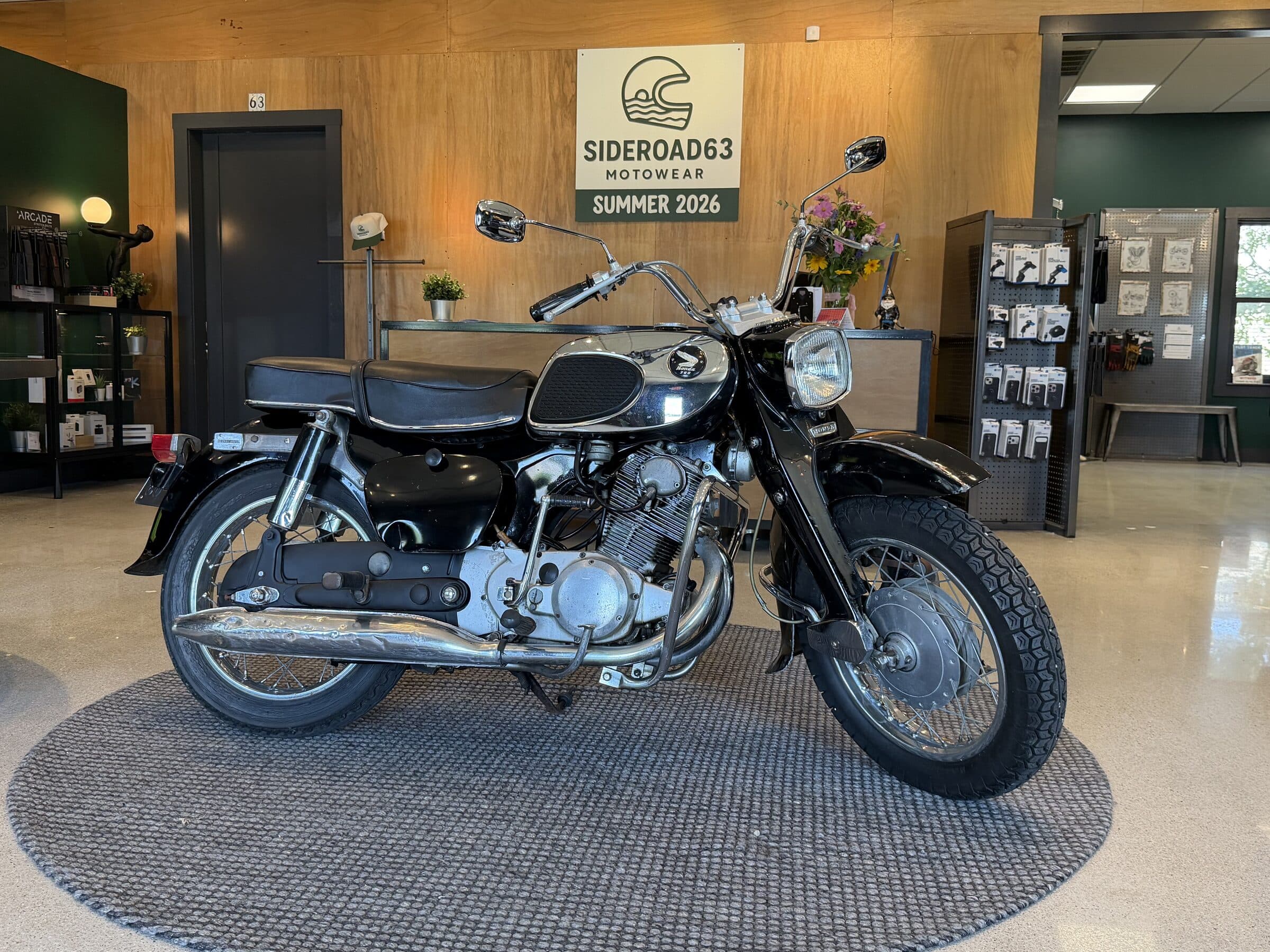 The 1963 Honda Dream parked on the SIDEROAD63 shop floor beneath the shop's sign
